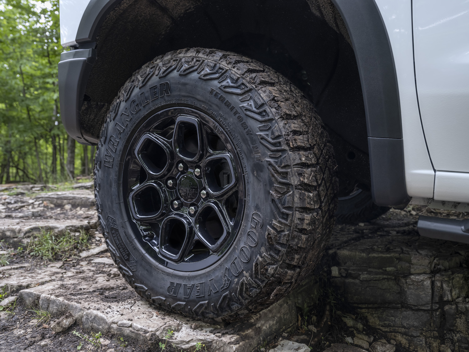 Closeup of the forged rim of a 2023 Chevrolet Silverado pickup truck with an off-road package, trees visible in the background.