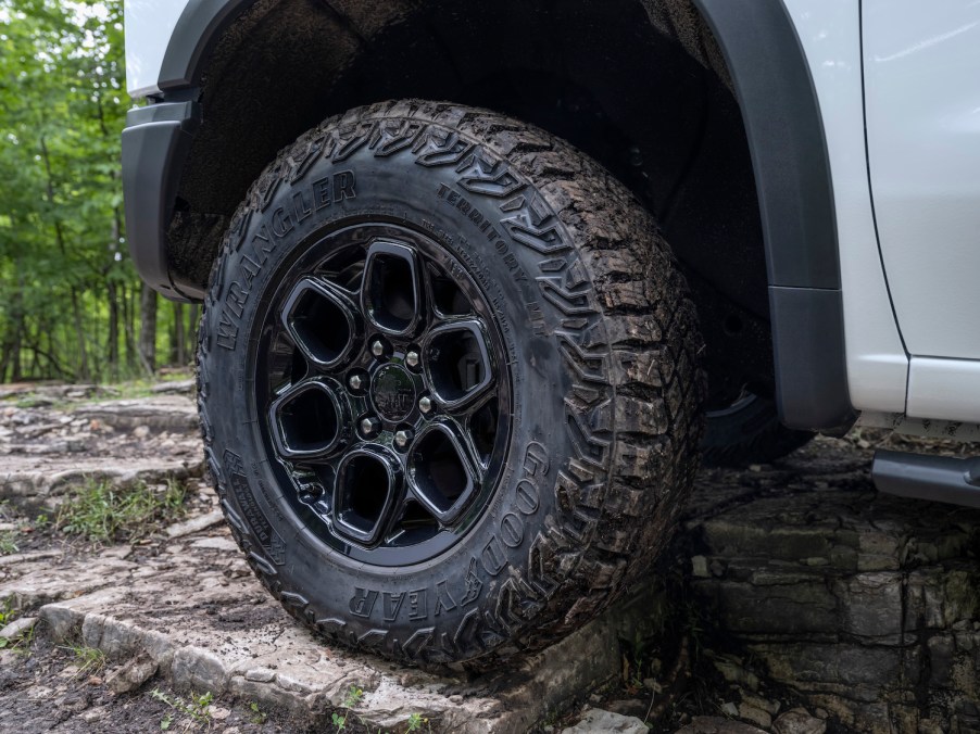 Closeup of the forged rim of a 2023 Chevrolet Silverado pickup truck with an off-road package, trees visible in the background.