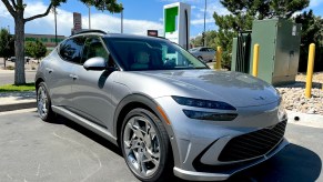 A front corner shot of the 2023 GV60 next to a Level 2 charger.