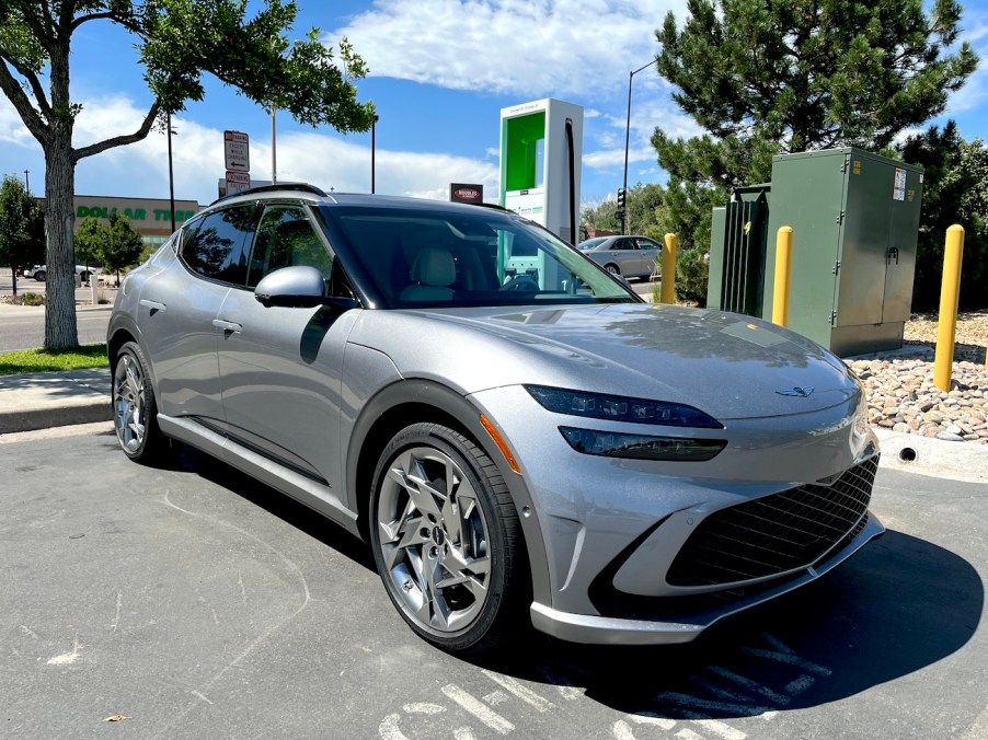 A front corner shot of the 2023 GV60 next to a Level 2 charger.