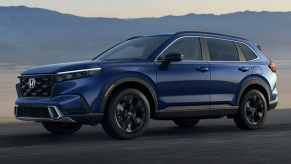 A blue 2023 Honda CR-V small SUV is driving on the road.