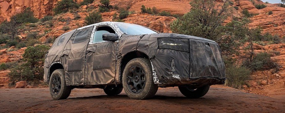 A camoflauge-wrapped 2023 Honda Pilot against trees.