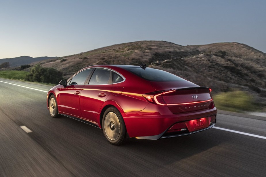 A red 2023 Hyundai Sonata Hybrid driving in the opposite direction