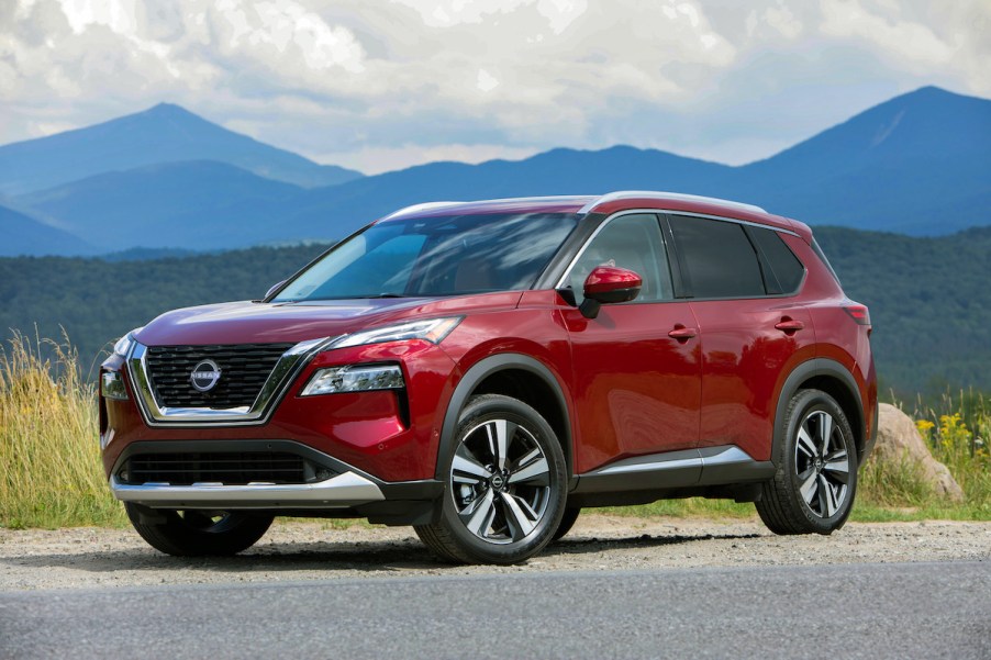 A red 2023 Nissan Rogue Sport parked in front of a mountainous landscape.