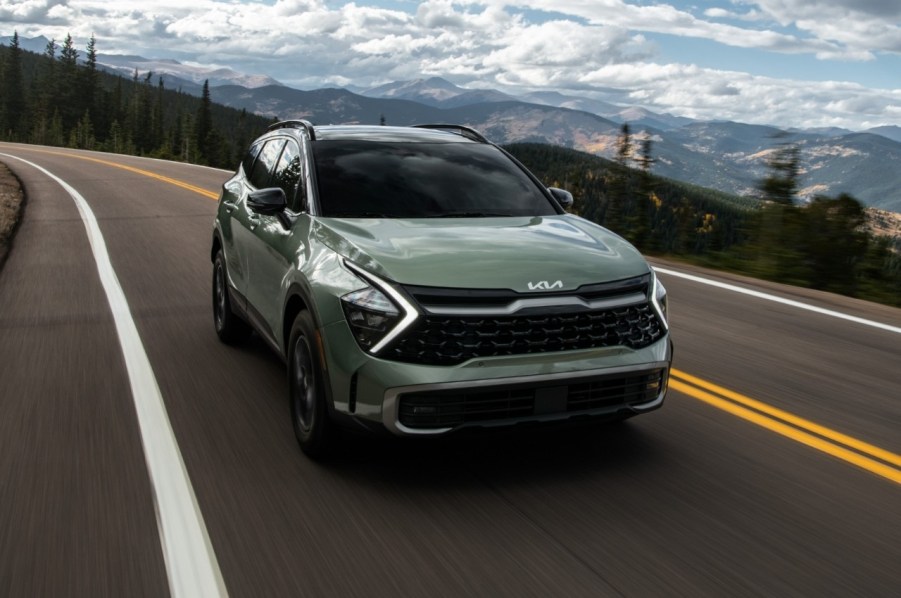 A green 2023 Kia Sportage driving down a highway.