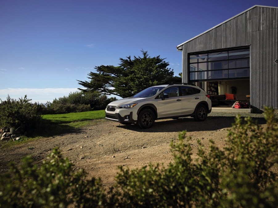 A 2023 Subaru Crosstrek parked in a dirt area in front of a barn-like building.