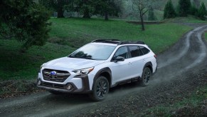 A white 2023 Subaru Outback driving down a road.