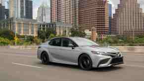 A silver 2023 Toyota Camry XSE Hybrid driving in a city