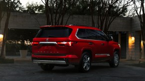 Red Toyota Sequoia full-size large hybrid SUV parked in a driveway at dusk.