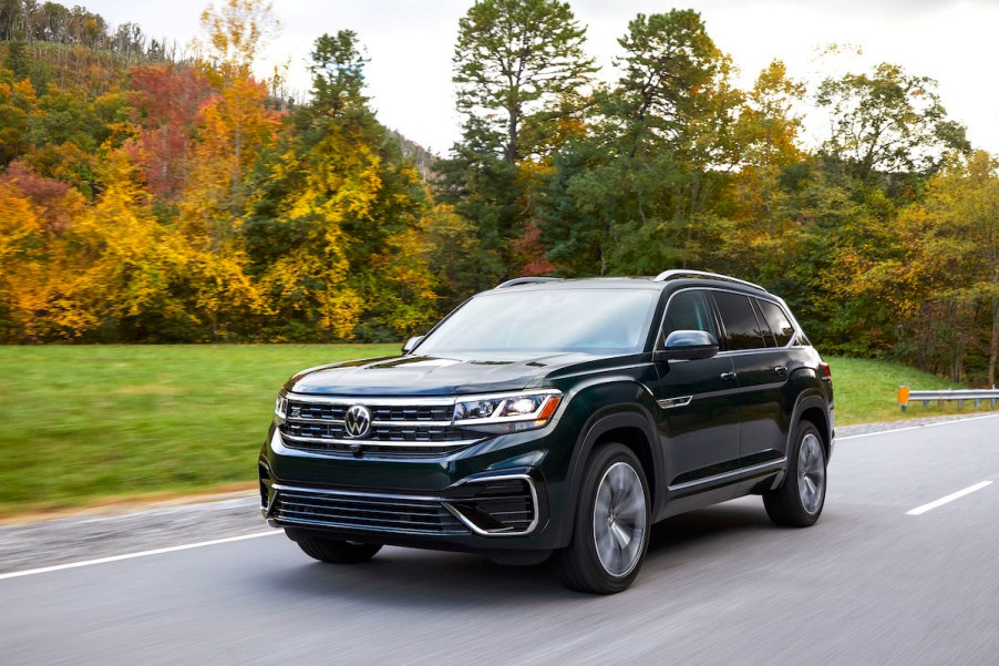 A dark colored 2023 Volkswagen Atlas driving down a road in a wooded area.