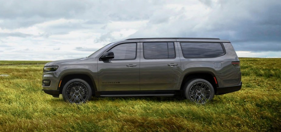 A gray 2023 Jeep Wagoneer L parked in a field. The longer wheelbase is one reason it's worth waiting for.