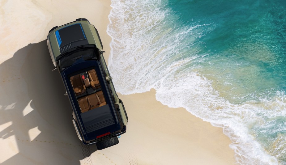 The top of a Jeep SUV parked by the ocean on a sandy beach.