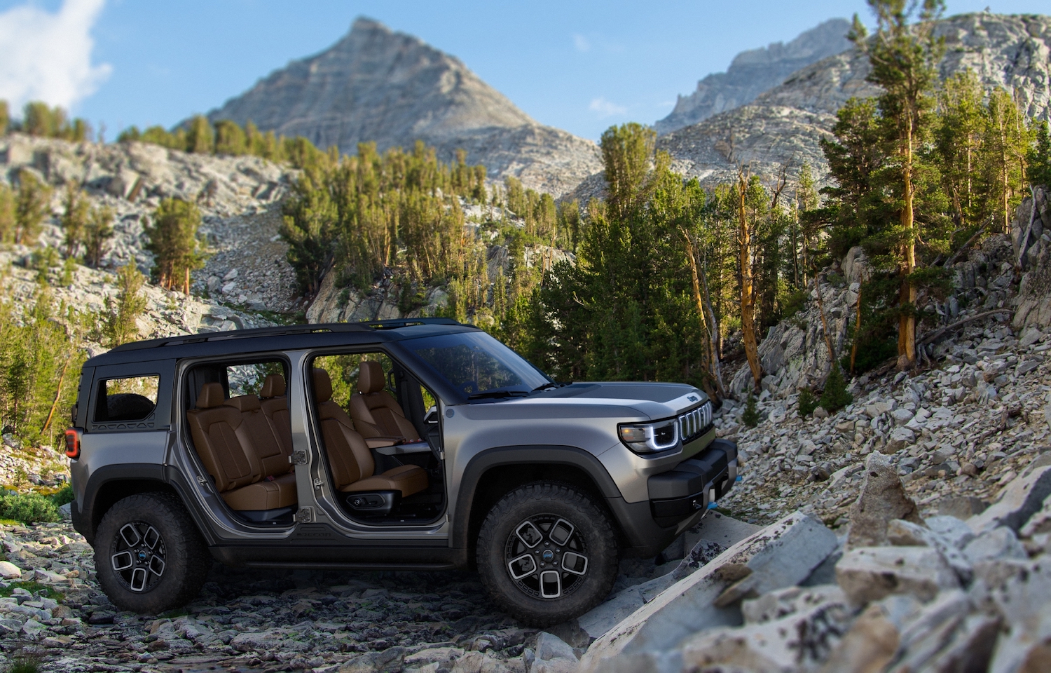 A Jeep Recon electric SUV on an off-road trail, mountains visible in the background.