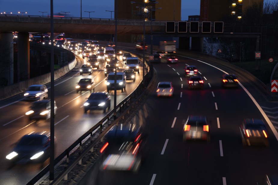 A busy highway at night, a city skyline visible in the background.