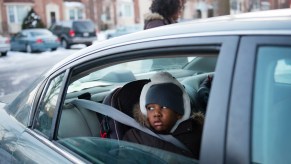 A person looking out of a open car window that may be subject to wind buffeting.