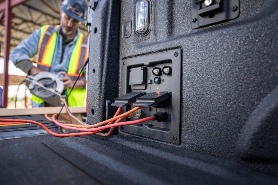 A construction worker plugs a skillsaw into an F-150 Powerboost.