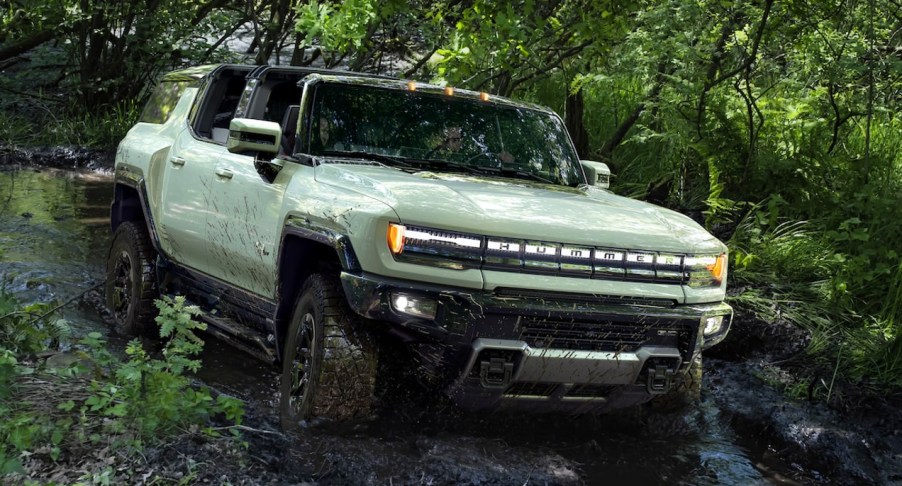 A green GMC Hummer EV is driving off-road.