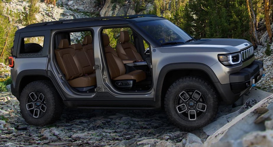 A gray Jeep Recon small electric SUV is parked outside. 