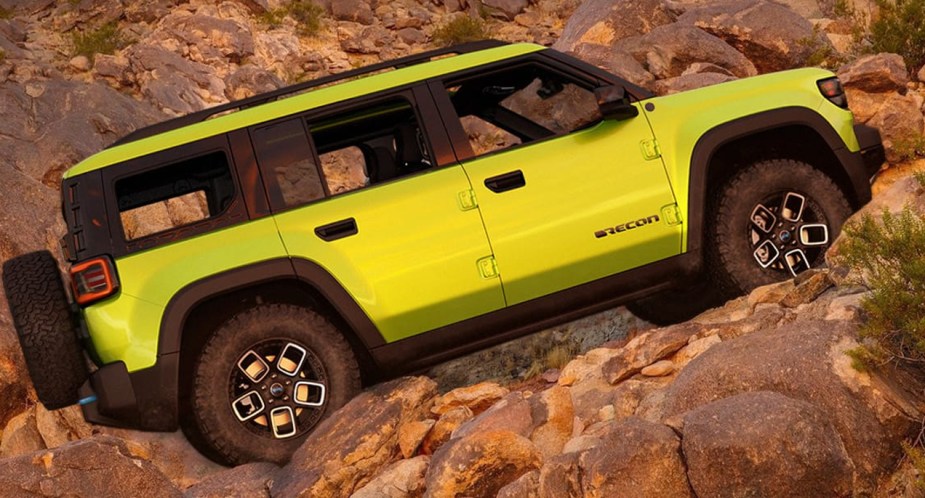 A green Jeep Recon fully-electric small SUV is driving up the hill. 