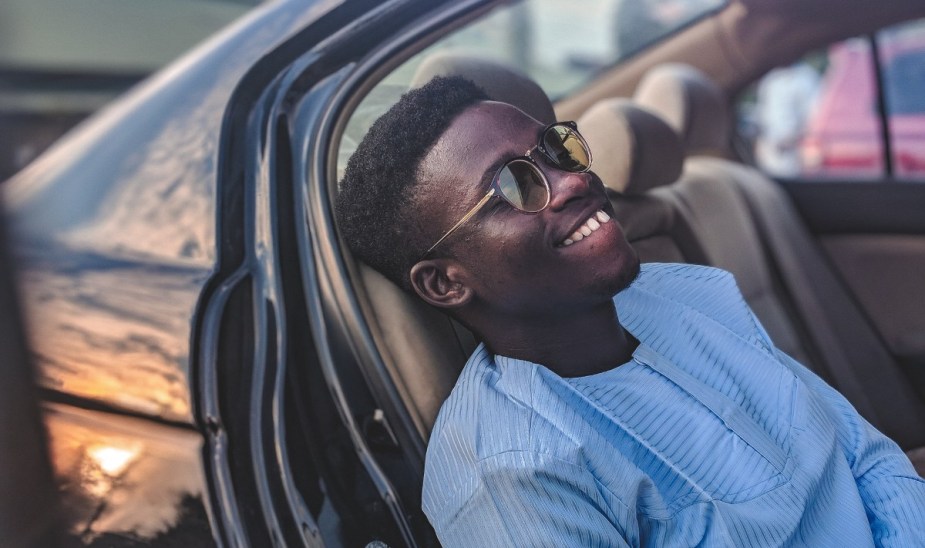 Man relaxing in back seat of car, highlighting why people sit in parked cars for a long time