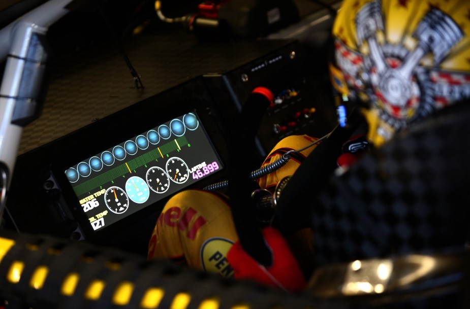 NASCAR driver Joey Logano looking at his digital dashboard, which does not have a speedometer.