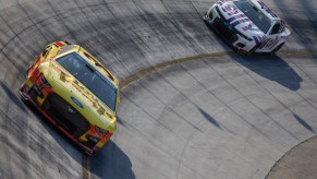 Two NASCAR Cup Cars completing practice laps at Bristol Motor Speedway before a race.