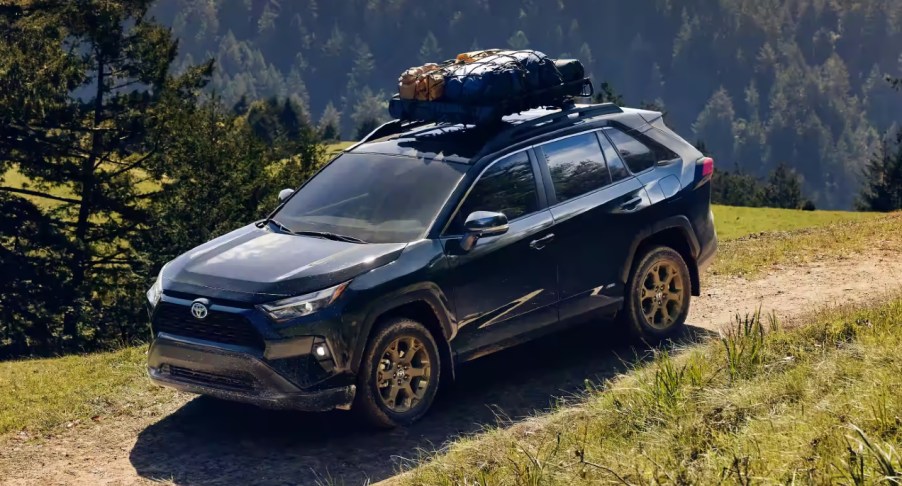 A blue 2022 Toyota RAV4 Hybrid Woodland Edition is driving off-road.