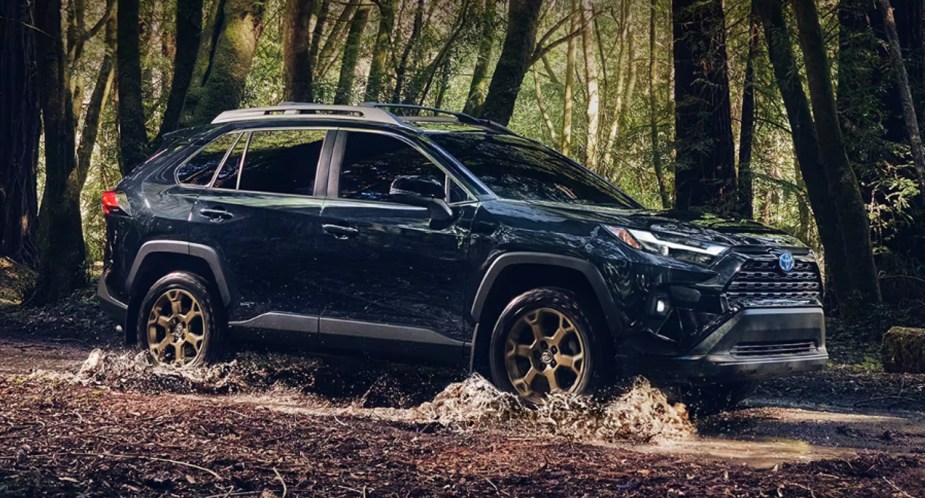 A blue 2023 Toyota RAV4 Hybrid Woodland Edition is driving off-road.