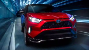 A red 2022 Toyota RAV4 Prime small plug-in hybrid SUV is driving.