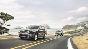 Promo photo of two Toyota hybrid SUVs driving together along a coastline, the ocean visible in the background.