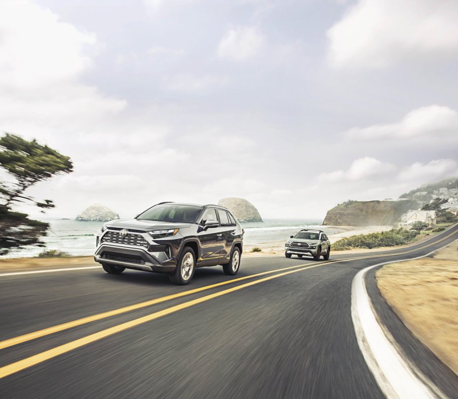 Promo photo of two Toyota hybrid SUVs driving together along a coastline, the ocean visible in the background.