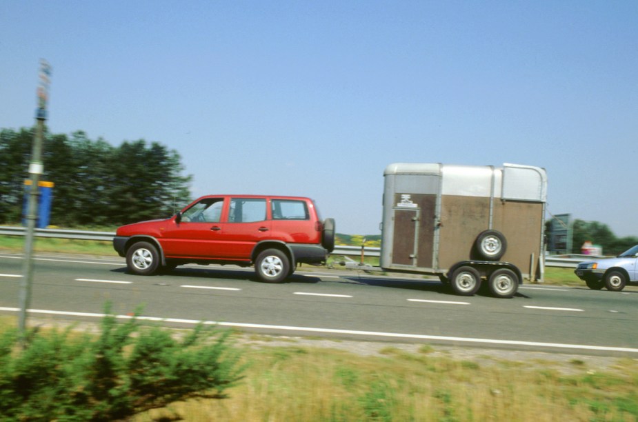 A vehicle that is towing a trailer on the interstate. 