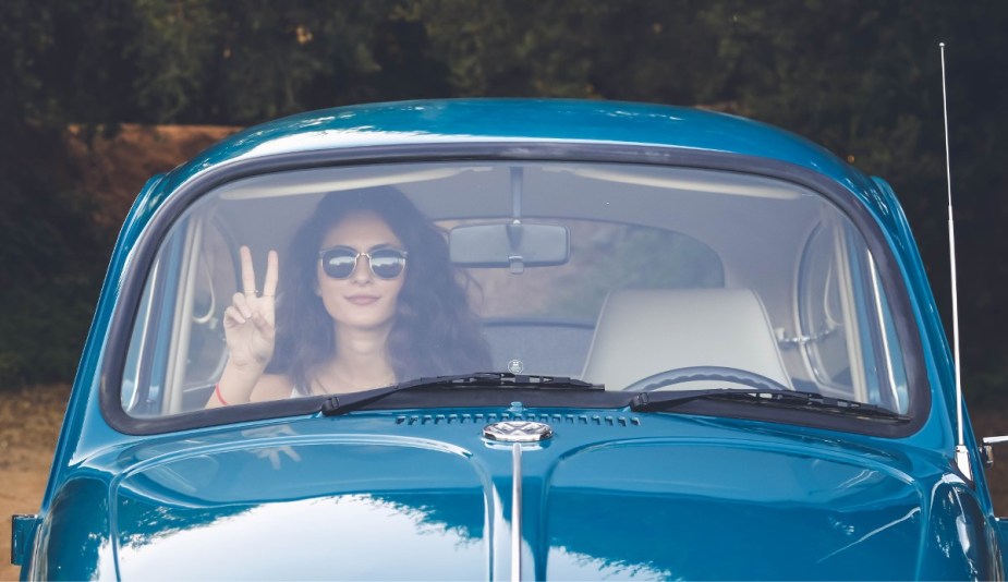 Woman sitting in VW Beetle, highlighting why people park and sit in their cars for a long time