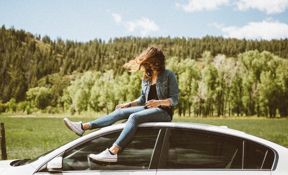 Woman sitting on roof of car, highlighting woman that talks to car like a person, as posted on Reddit