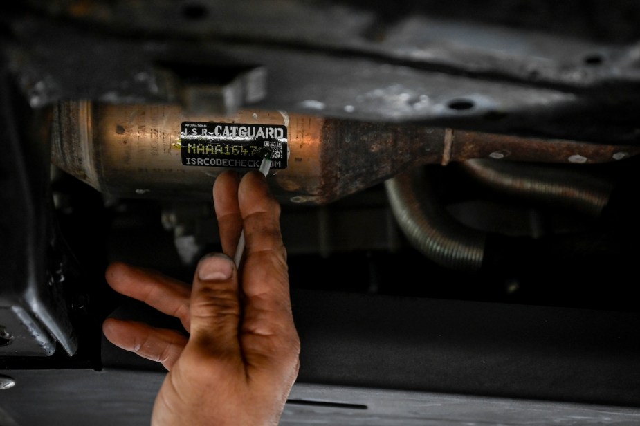 A mechanic places a sticker on the catalytic converter of a Toyota Tacoma.