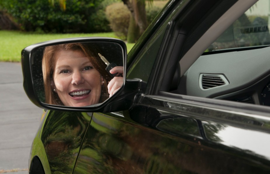 A happy driver holds up her car key. 