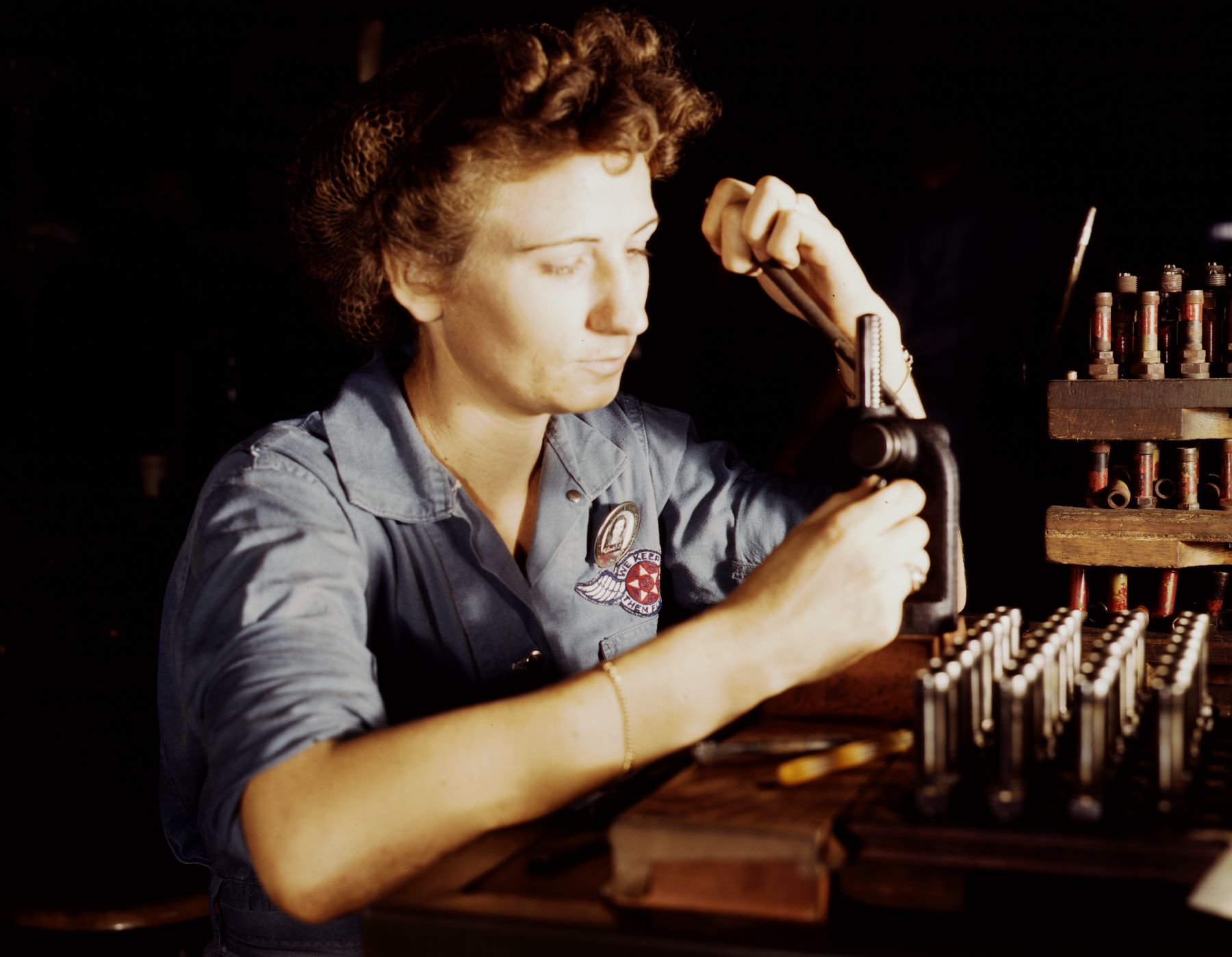 A female service worker reconditioning spark plugs at a Navy Air Base