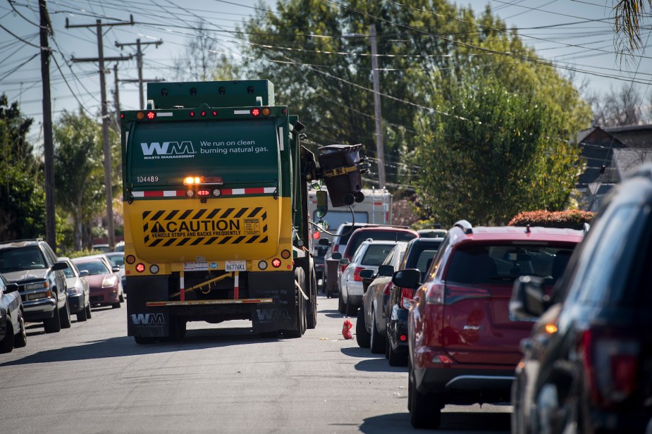 Garbage truck pickup up a garbage can on a suburban street in Hayward, California.