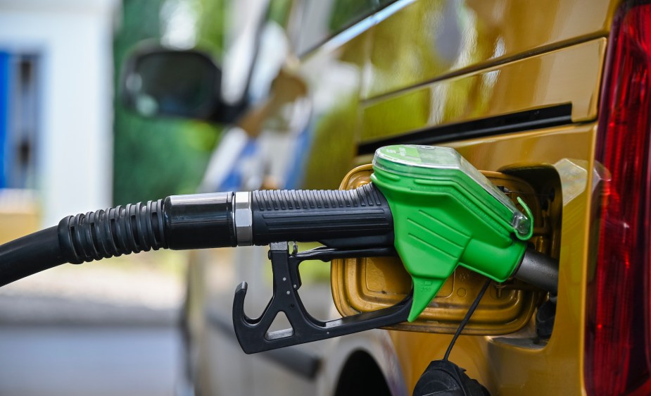 A person pumping gas, potentially getting bad gas mileage. 