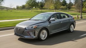 A gray 2018 Hyundai Ioniq Hybrid compact sedan driving past a park