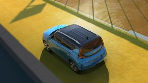 An overhead shot of a blue 2023 Kia Soul subcompact SUV/MPV on a strip of yellow road