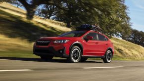 A red 2023 Subaru Crosstrek Premium compact SUV model with a roof rack driving down a highway