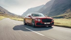 A red Bentley Flying Spur V8 high-performance luxury sports car driving on an open country highway