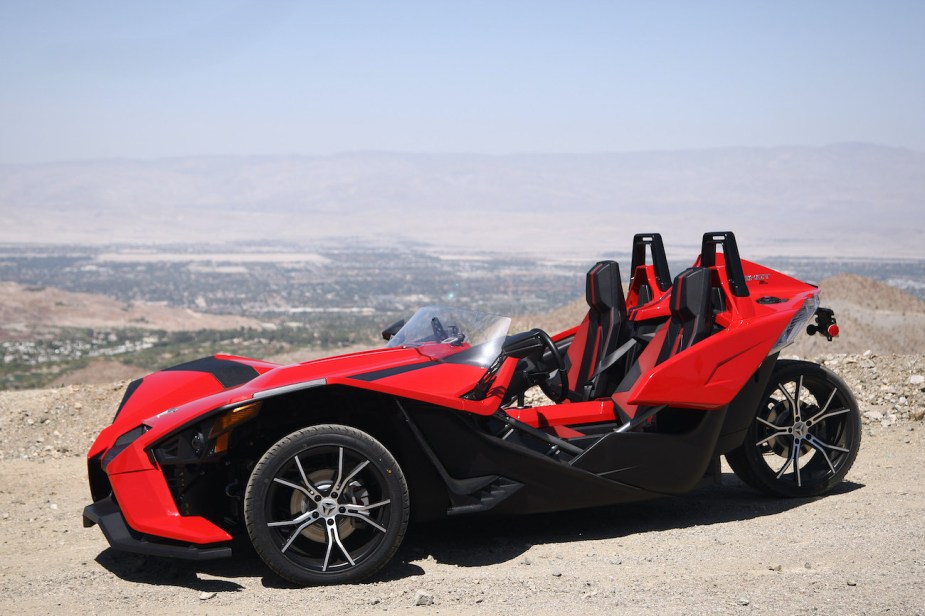 A red Polaris Slingshot poses in the desert.