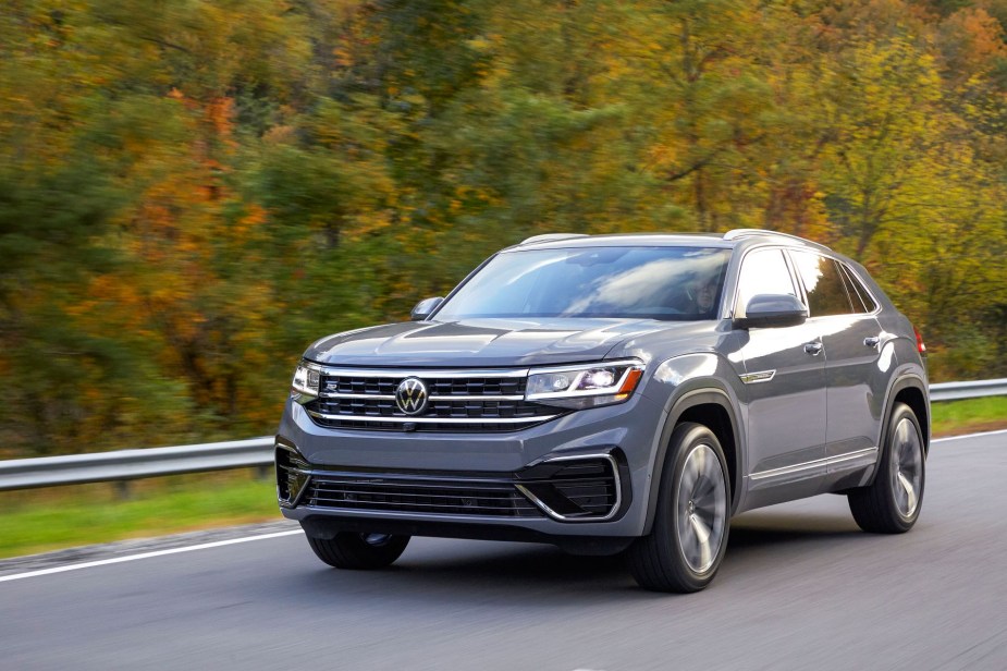 A gray 2022 Volkswagen Atlas Cross Sport premium two-row midsize SUV model driving on a forest highway road