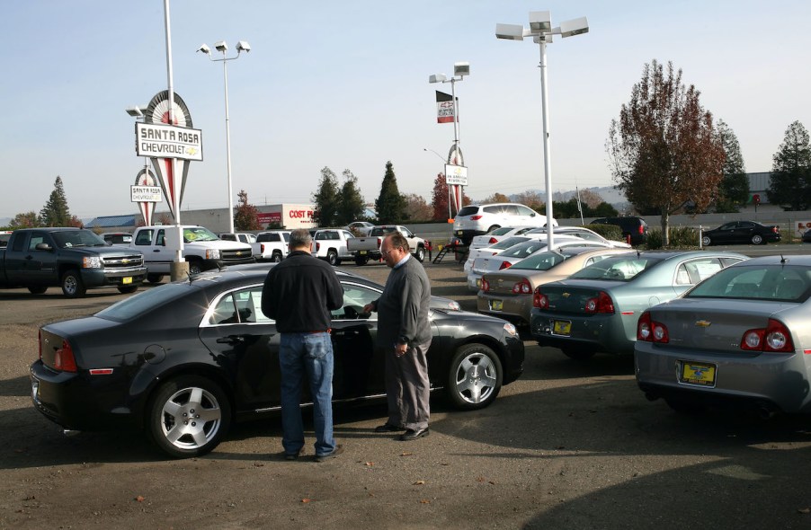 A car salesman talks to a customer about trading in a car.