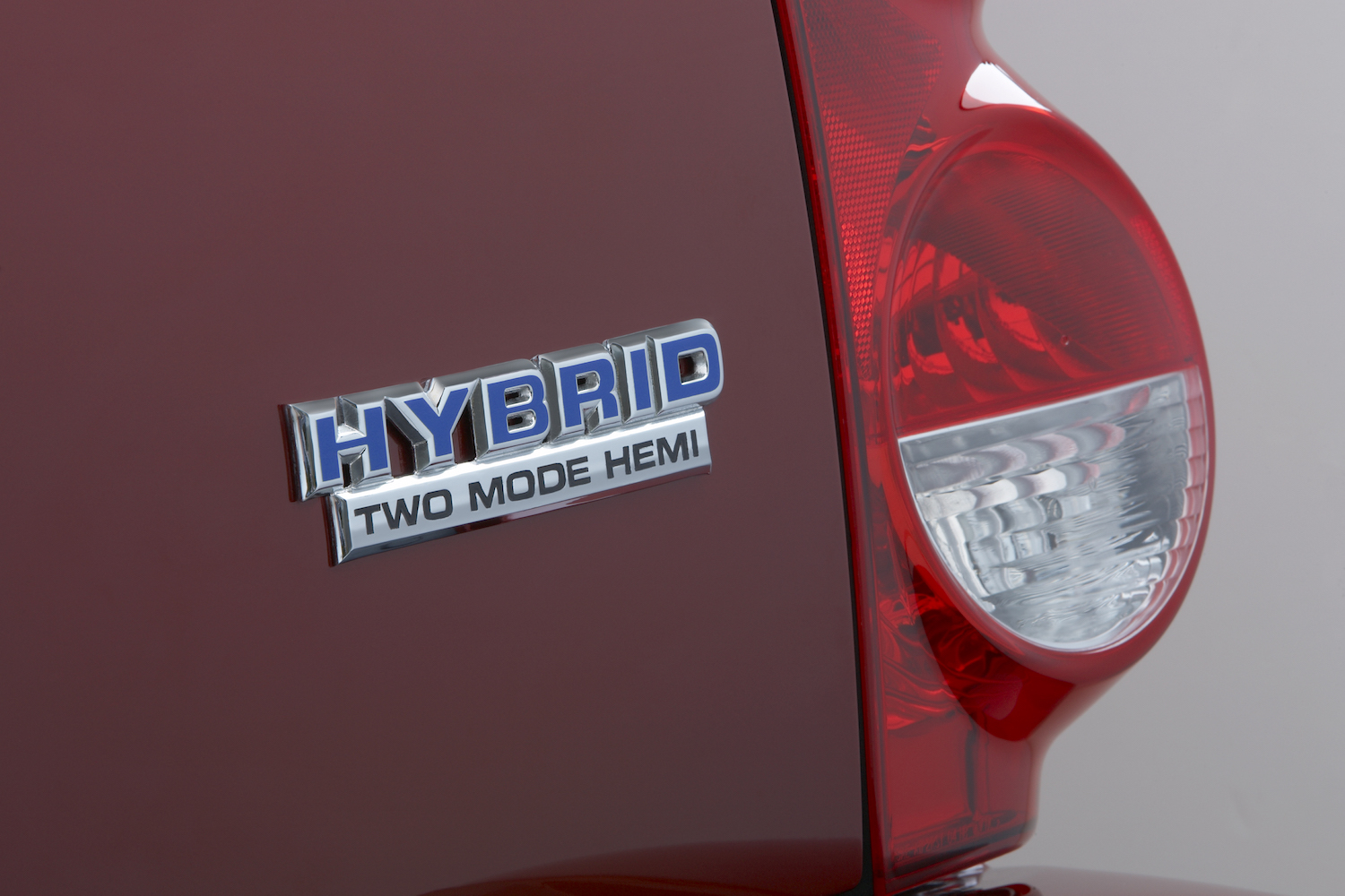 Closeup of a chrome "Hybrid Two Mode Hemi" badge on the rear of a red 2009 Dodge Durango full-size V8 SUV, one taillight visible as well.