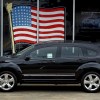 A black 2010 Dodge Journey parked in front of window with an American flag in the window.