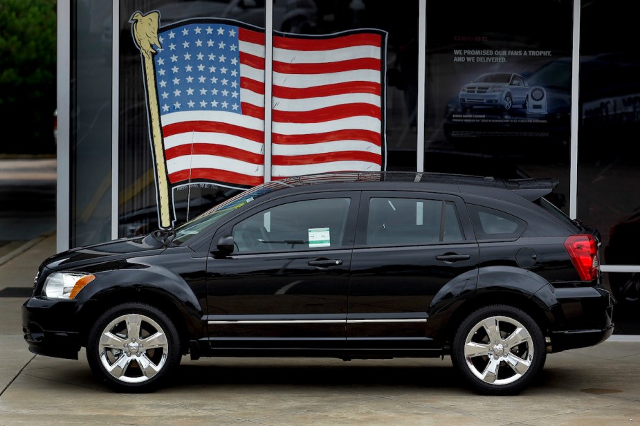 A black 2010 Dodge Journey parked in front of window with an American flag in the window.