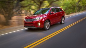 A red 2014 Kia Sorento used midsize SUV driving